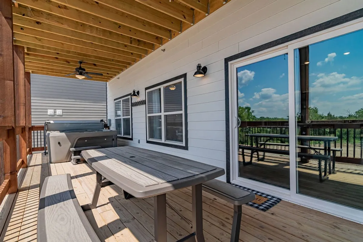 An outdoor deck featuring a dining table, grill, and large sliding door that opens directly from the house. The deck is set up for outdoor dining, barbecues, and enjoying views of the surrounding landscape, making it a natural extension of the living and dining spaces inside.