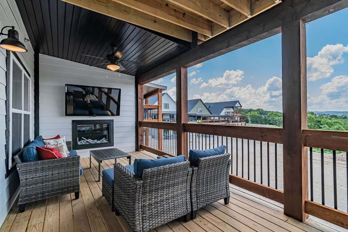 An exterior deck with woven seating, a flat-screen TV, an outdoor fireplace, and expansive views of the surrounding landscape. The space is perfect for relaxing, outdoor dining, or savoring the view—ideal for morning coffee or evening get-togethers.