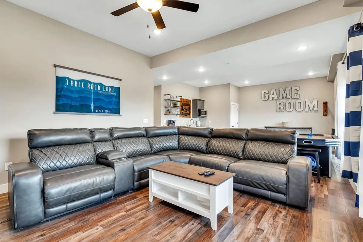 Featuring a large sectional sofa, a prominent 'game room' sign, and a coffee table, this image portrays the inviting atmosphere for group relaxation, board games, or movie nights after gaming sessions.